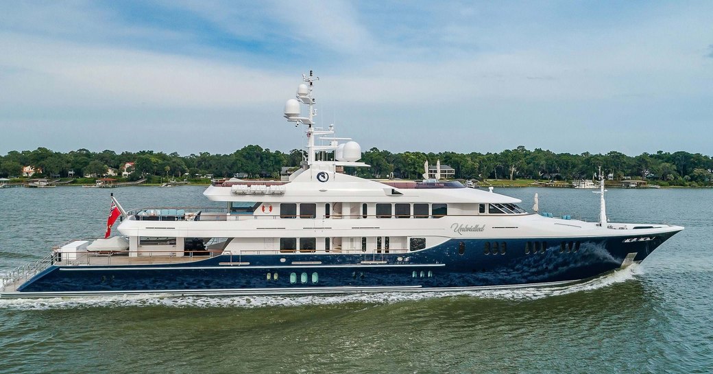 Charter yacht UNBRIDLED underway, surrounded by sea with land in the background.