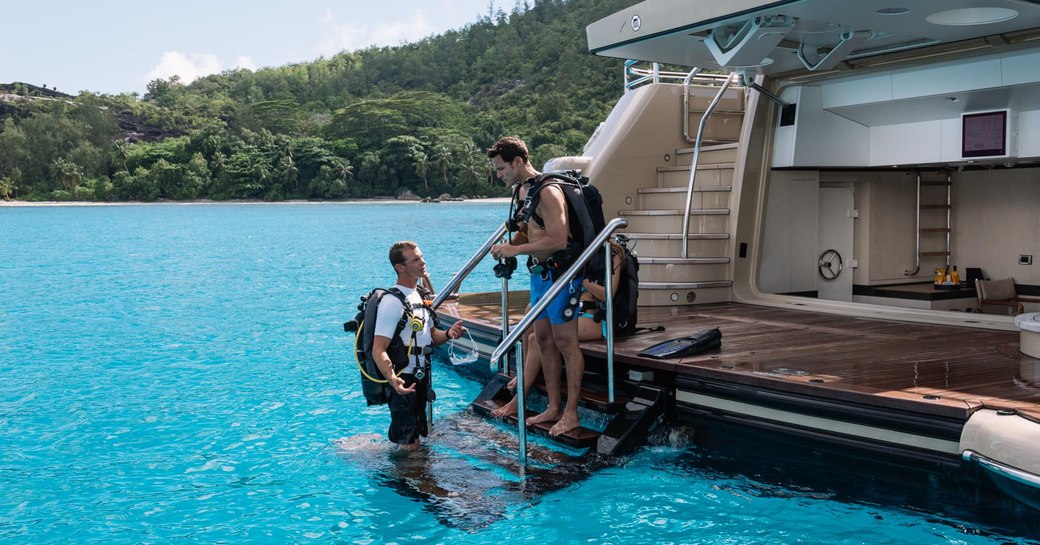 charter guest on swim platform of charter yacht LILI gets ready to go diving with crew member