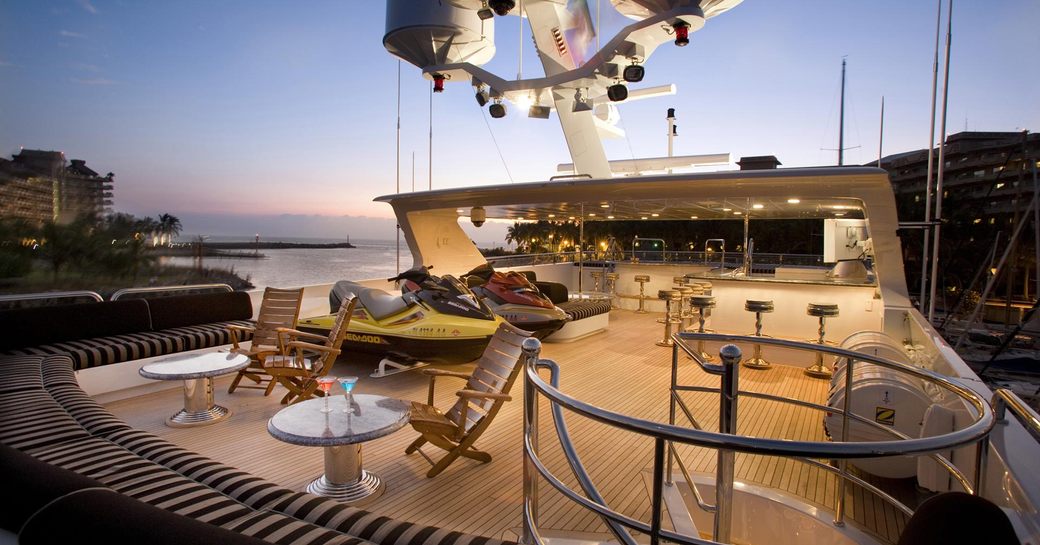 Superyacht sundeck, with cocktail tables and sofa seating, as well as two bars and Water-Ski storage