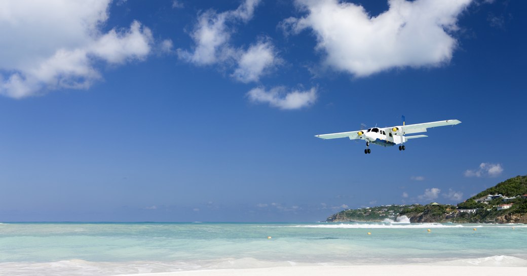 small chartered flight/ private plane arriving into the caribbean above sandy beach and blue sea