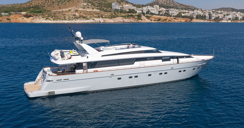 Charter yacht GRACE at sea with elevated terrain in the background