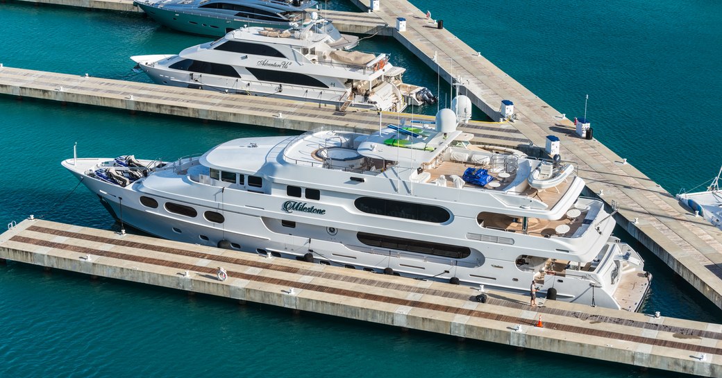 Row of four motor yachts and superyachts moored along a pontoon, surrounded by sea