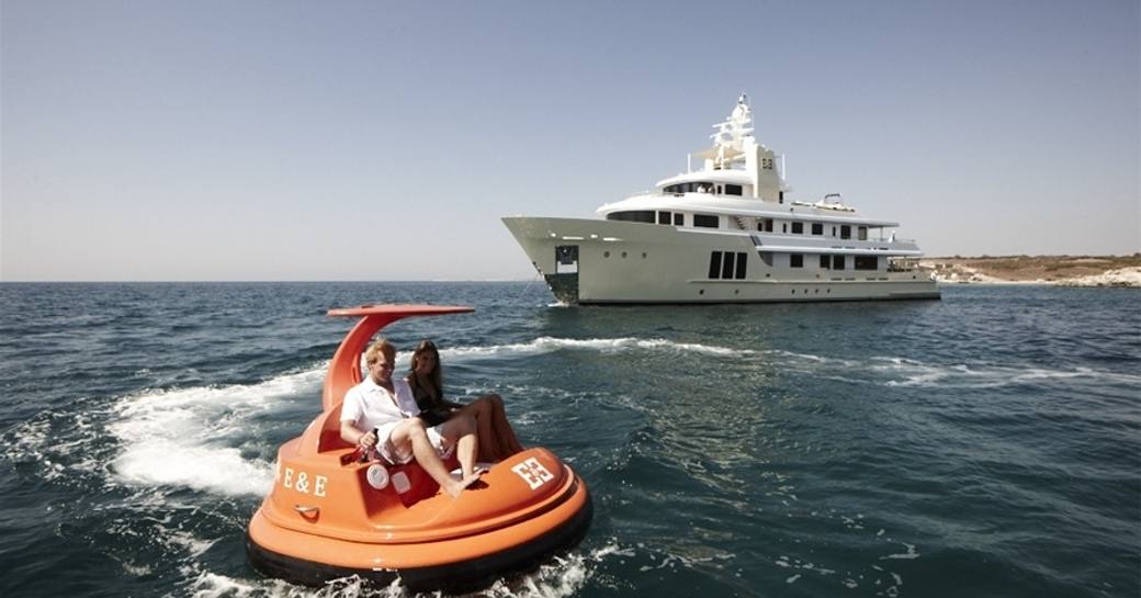 luxury yacht E&E anchors on charter while guests play on water toys