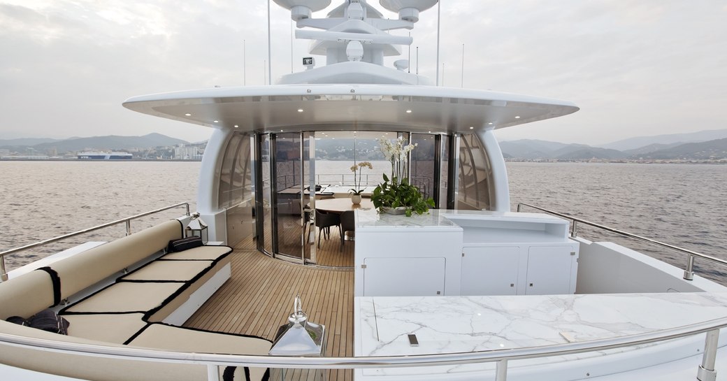 alfresco seating and dining area with glass windbreak on sundeck of motor yacht OKKO 