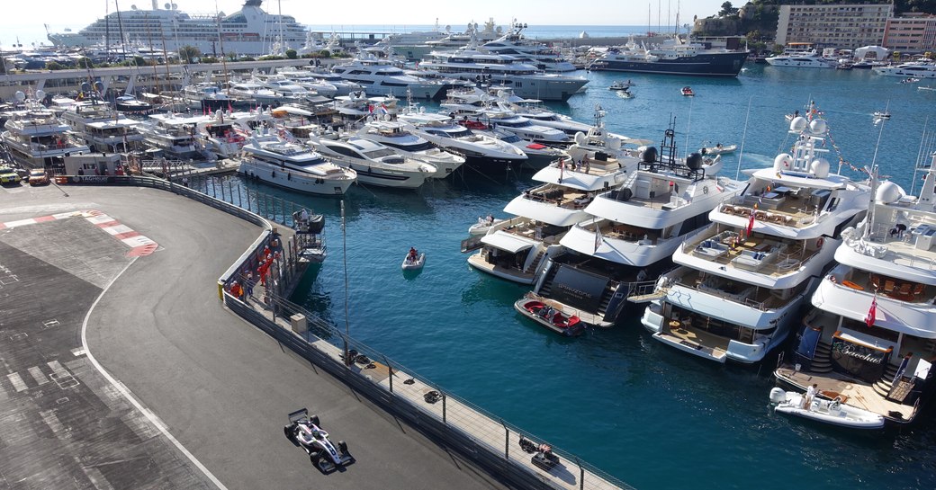 car drives past superyachts lined up in Port Hercules as part of the Monaco Grand Prix