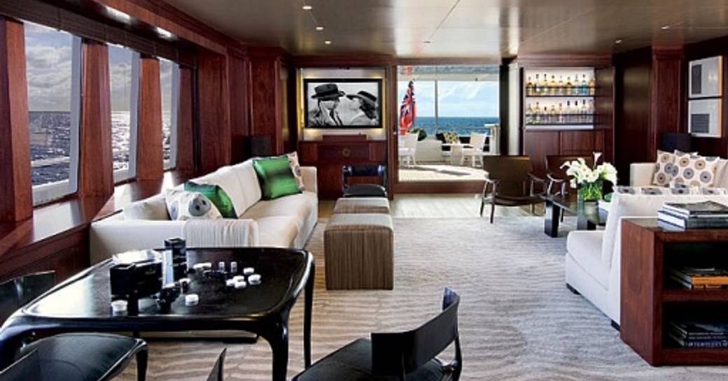 Overview of the upper salon onboard yacht charter CYAN with plush seating and a games table in the foreground