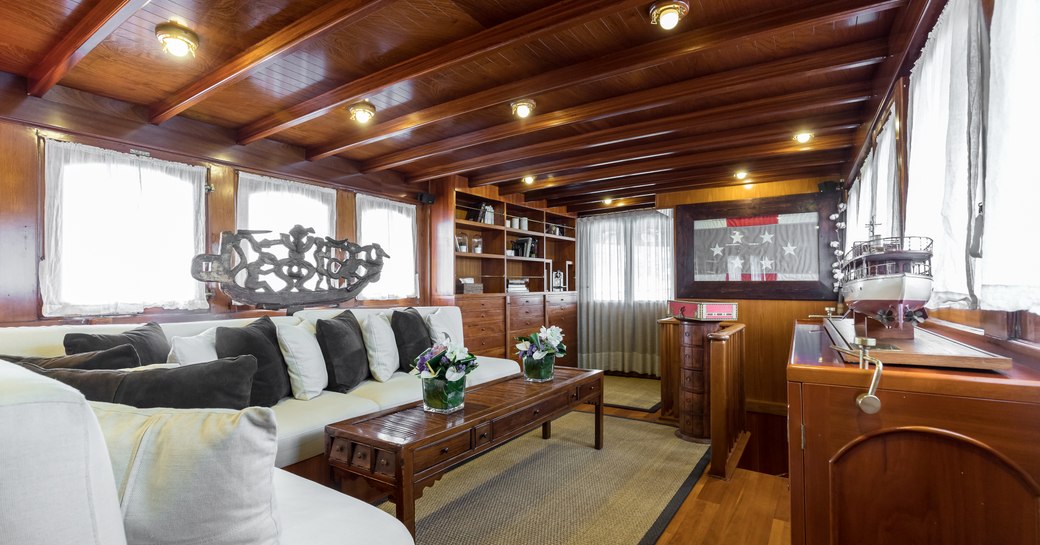 classic motor yacht over the rainbow main salon with polished wood surfaces, white sofas and flag framed on wall