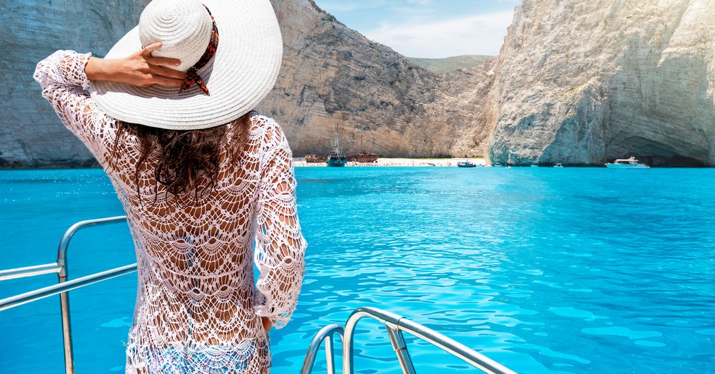 Woman on bow of yacht nears Shipwreck beach in Zakynthos, Greece