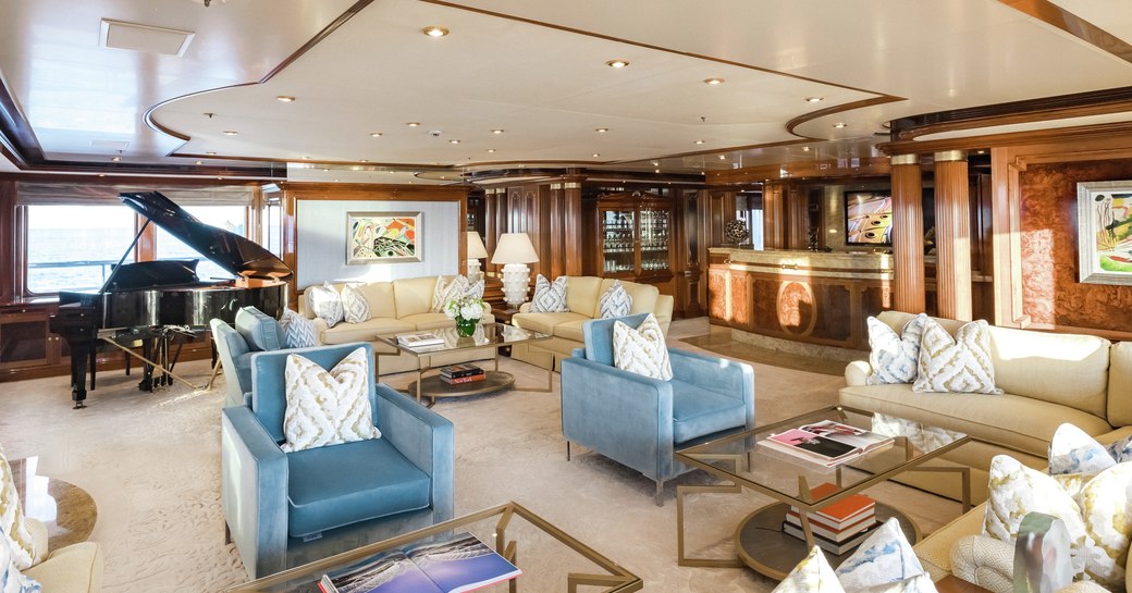 main salon with sofas and armchairs and piano on board superyacht TITANIA