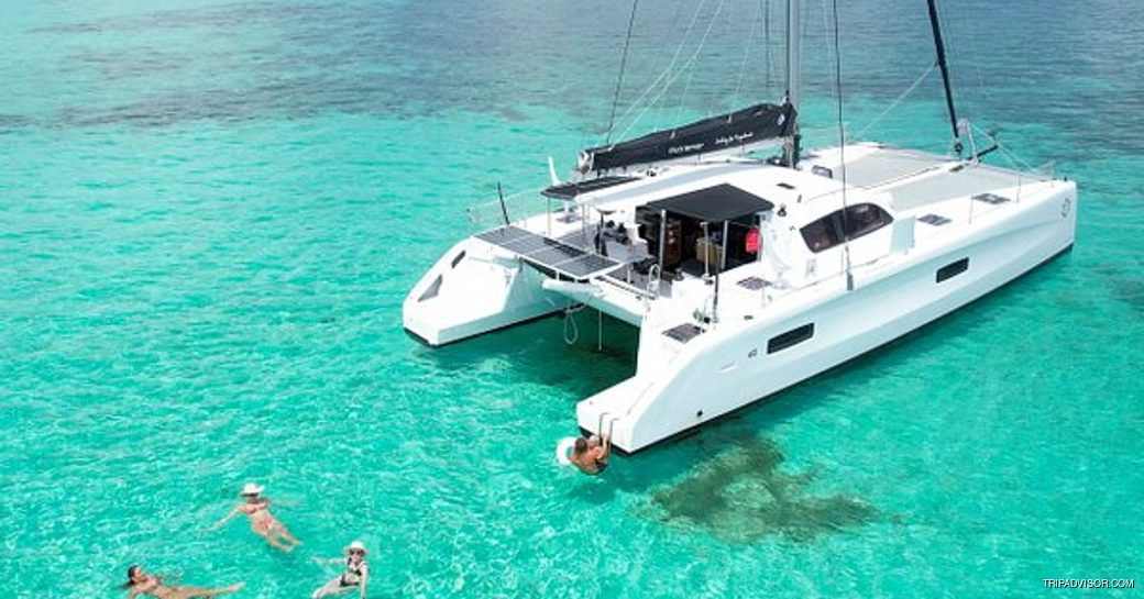 Four people swimming in turquoise blue water by a yacht in Marsh Harbour 