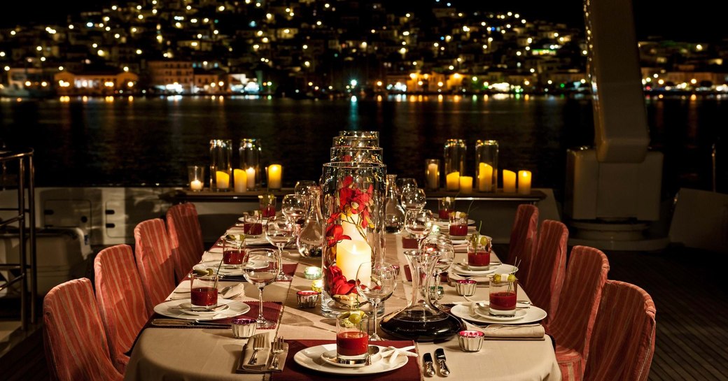 mediterranean coastlines lit up, with yacht and dining set up in foreground