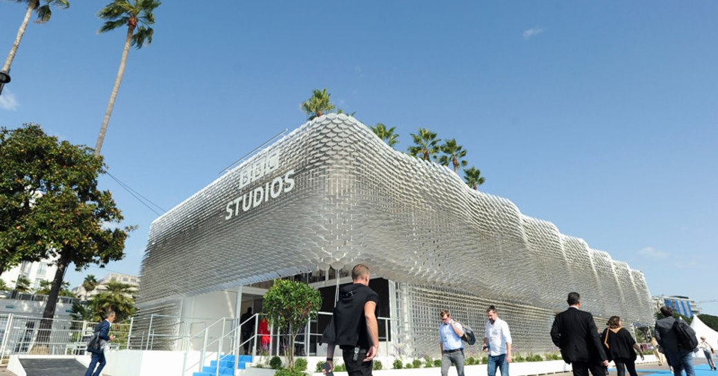 Exterior view of BBC Studios stand at MIPCOM, visitors walking along blue carpet outside.