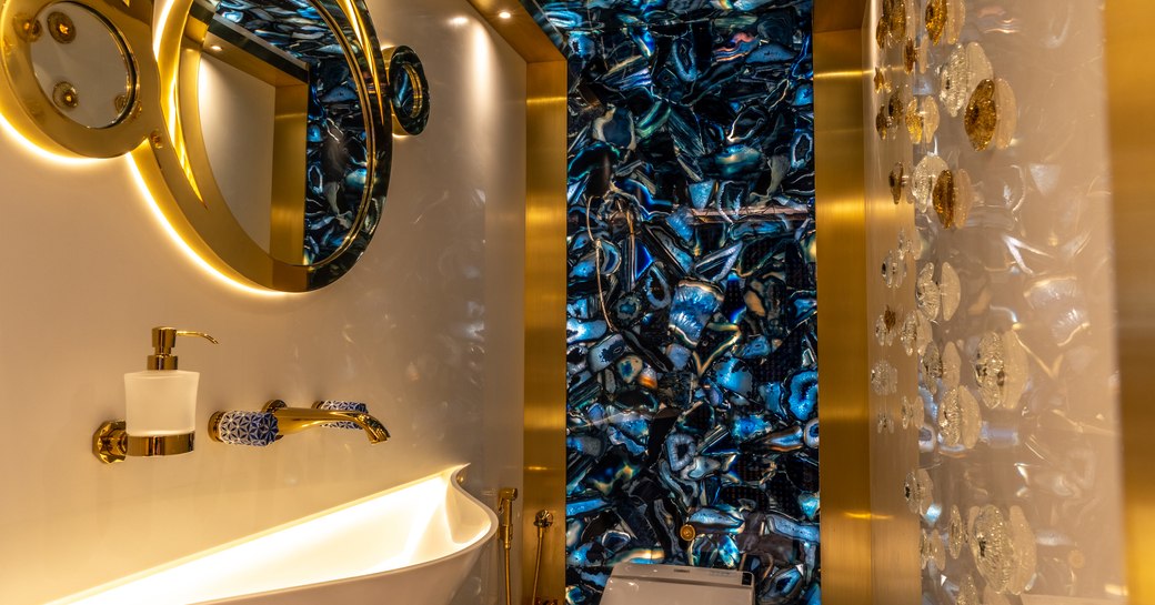 Central bathroom onboard superyacht LEONA, with blue tiles and gold finishing.