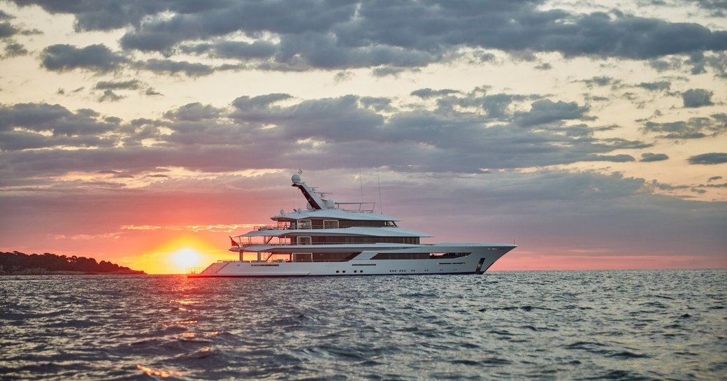 orange sun setting behind the luxury charter yacht as it cruises the waves of st lucia