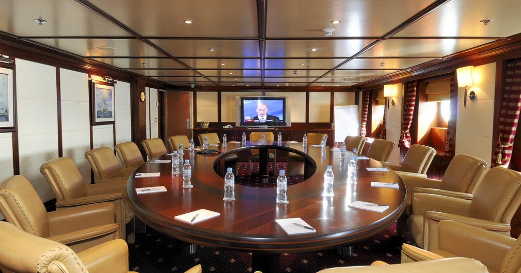 Conference room with water bottles and brown leather chairs on board charter yacht Lauren L