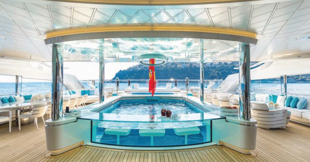 bright and airy shot of designer swimming pool surrounded by off white and cream couture seating on charter yacht Lady S