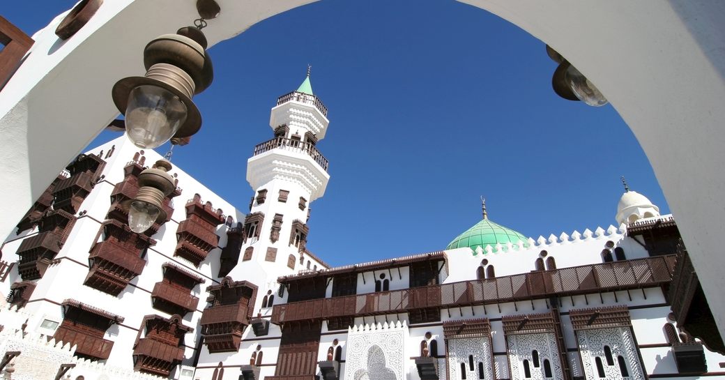 Ground level view of Jeddah architecture, with blue sky above.