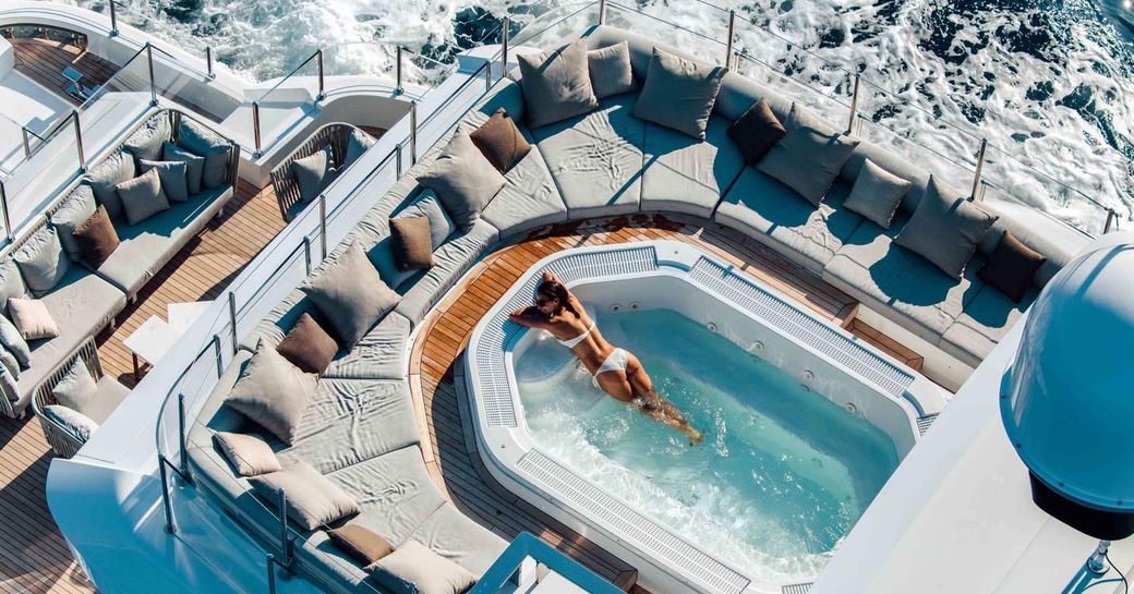 charter guest relaxes in pool on superyacht while social distancing