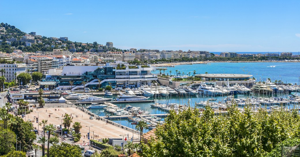 Overview of Cannes marina, with multiple yachts moored in berths, surrounded by sea.