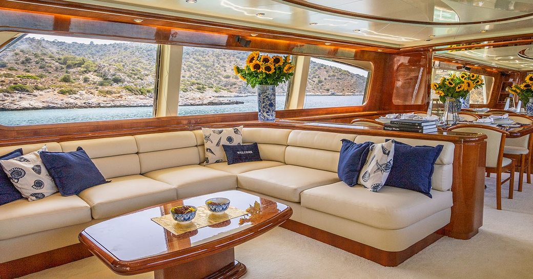 Main salon onboard boat charter ESTIA POSEIDON with cream sofas and extensive glazing