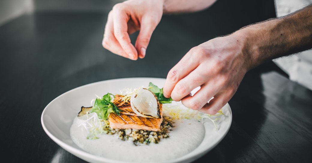 Chef finishing off a plate of Michelin cuisine.