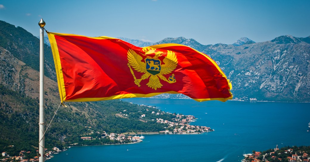 A Montenegrin flag waves in the wind above spectacular coastal landscape