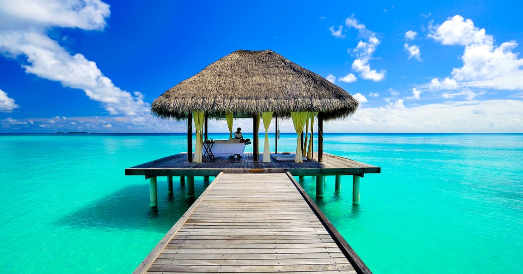 Wooden pier stretching out over turquoise waters in the maldives