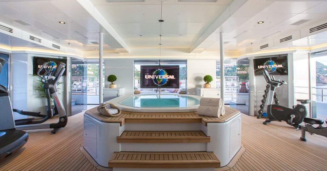 pool on deck of luxury yacht naia, with tv screen and gym equipment