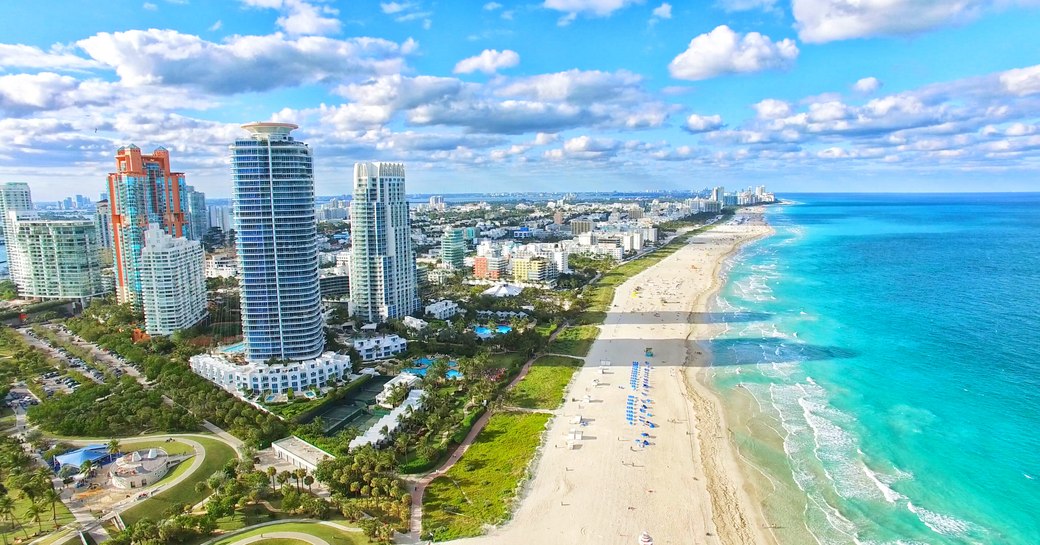 Overview of South Beach, Florida. Sandy beach adjacent to towering hotels and teal sea.