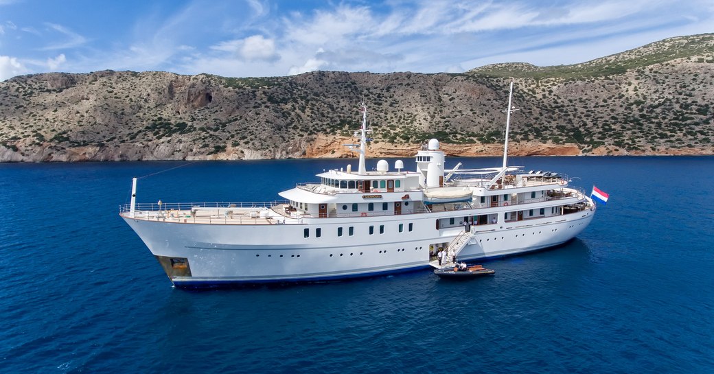 The luxury motor yacht Sherakhan at anchor near a rocky shore