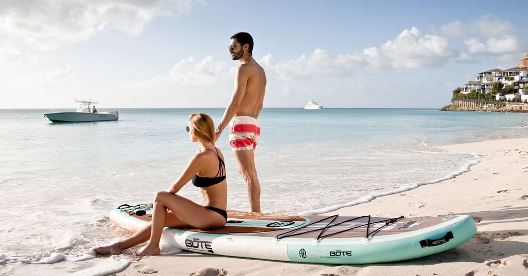 charter guests aboard TOUCH relax on a beach after paddle-boarding to the shore