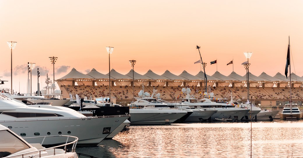 Superyachts in Yas Marina at sunset, with views over the water and grandstands in the background