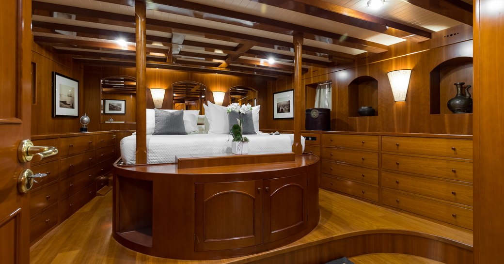 master stateroom on luxury charter yacht over the rainbow, view of four poster king size bed and storage units built into the walls