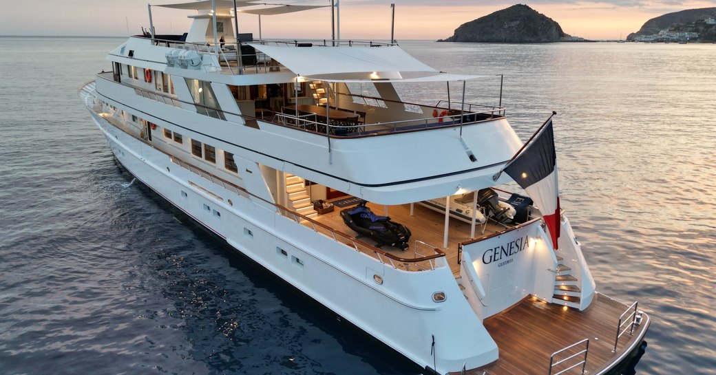 Aft angle view of charter yacht GENESIA at anchor, surrounded by sea with small islands in the distance