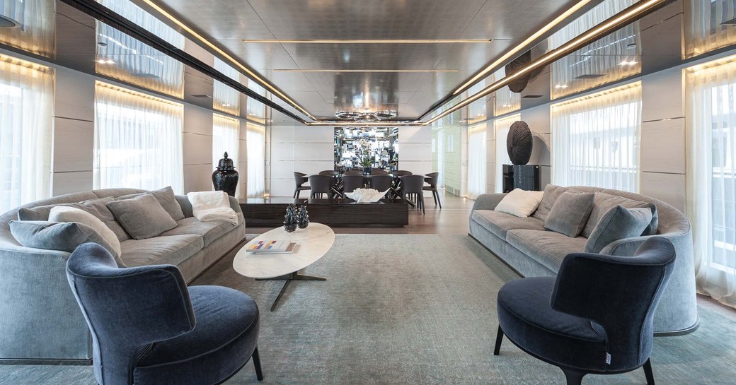 two grey sofas and two navy blue armchairs in the main salon of superyacht ENTOURAGE 