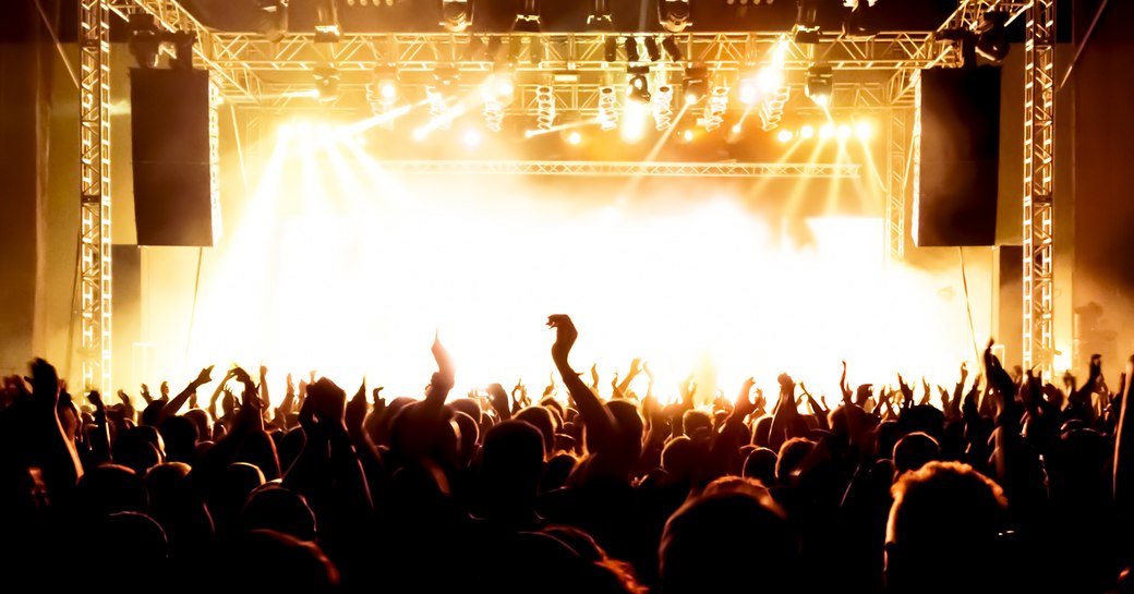 Rock concert, silhouettes of happy people raising up hands