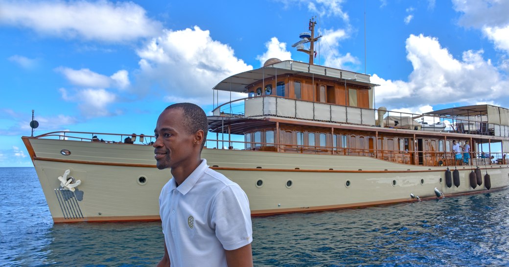 man on tender infront of luxury yacht over the rainbow, at anchor near thanda island