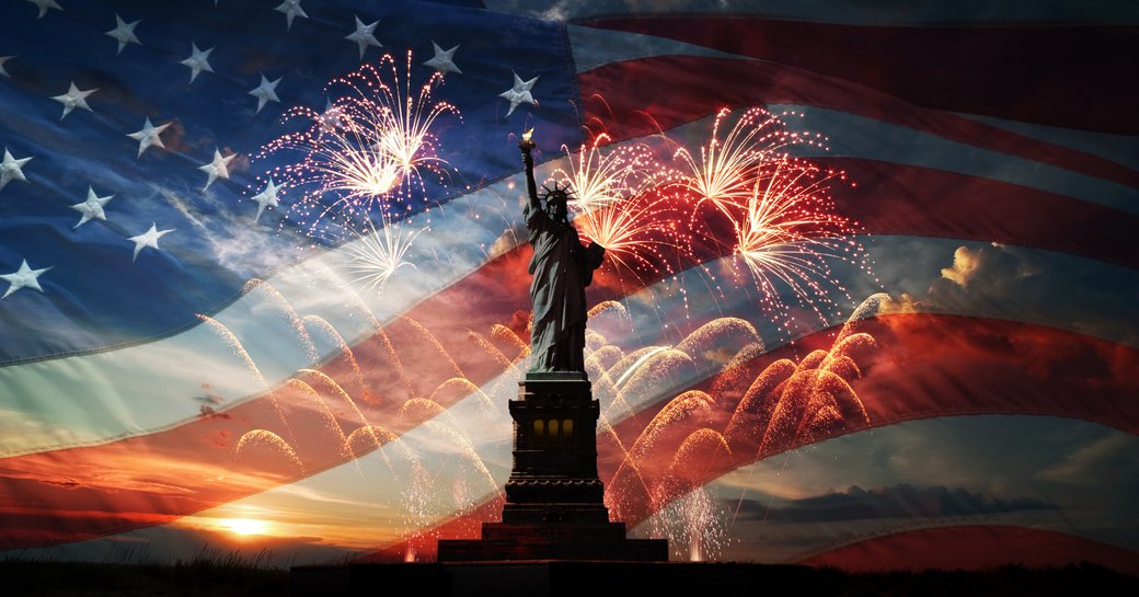 Statue of Liberty with American flag and fireworks at night