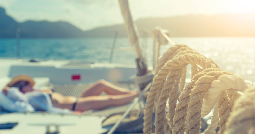 charter guests relaxes on deck of a sailing yacht while cruising in the Whitsundays