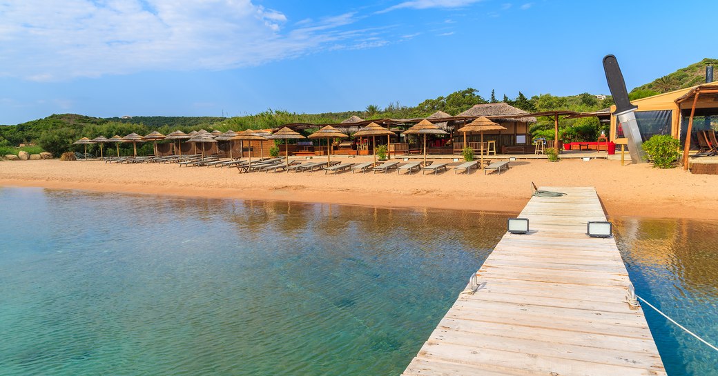 a beach along Santa Manza with a boardwalk and sun loungers