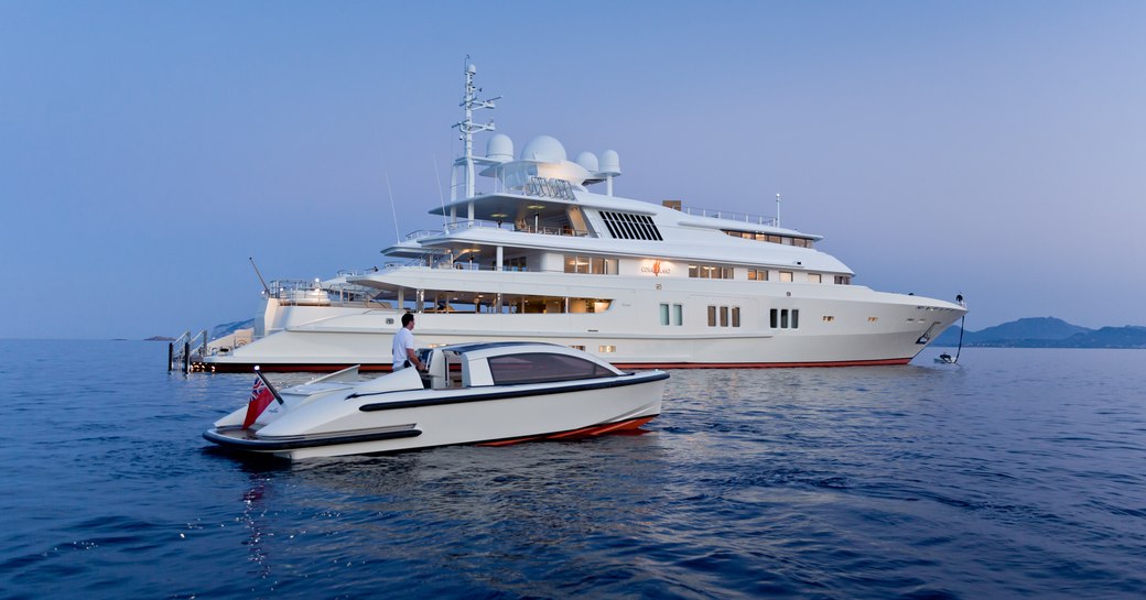 luxury yacht Coral Ocean cruising alongside tender on a luxury yacht charter in Antigua