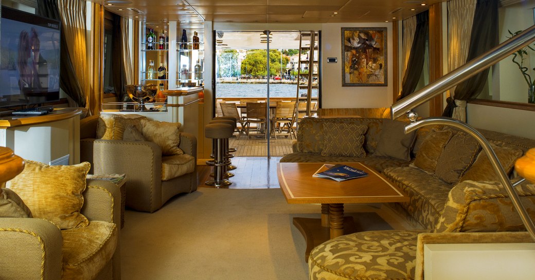 the plush and deluxe main salon of charter yacht carmen fontana with sofa, armchairs and state of the art entertainment system