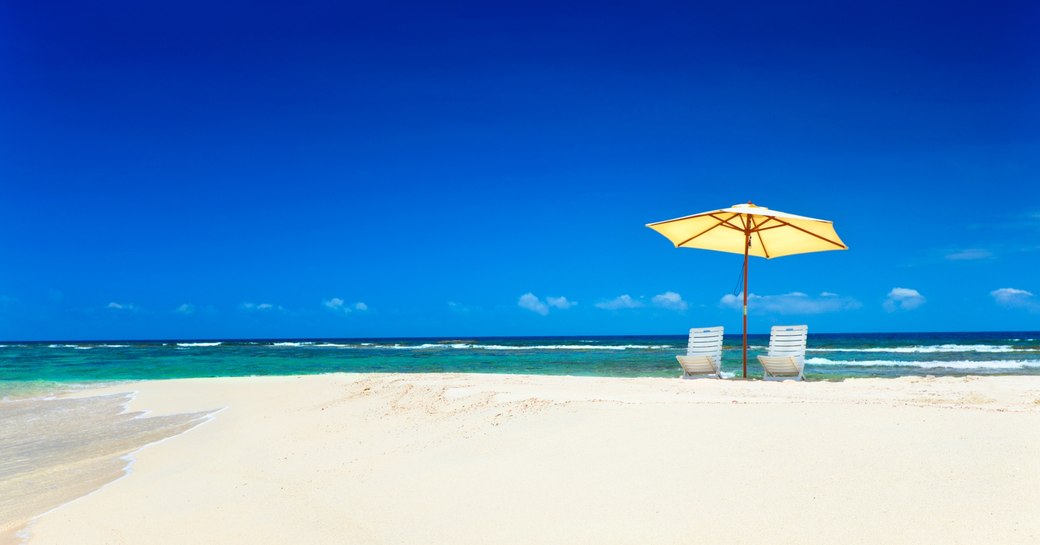 Idyllic caribbean beach with white sand and two sun loungers 