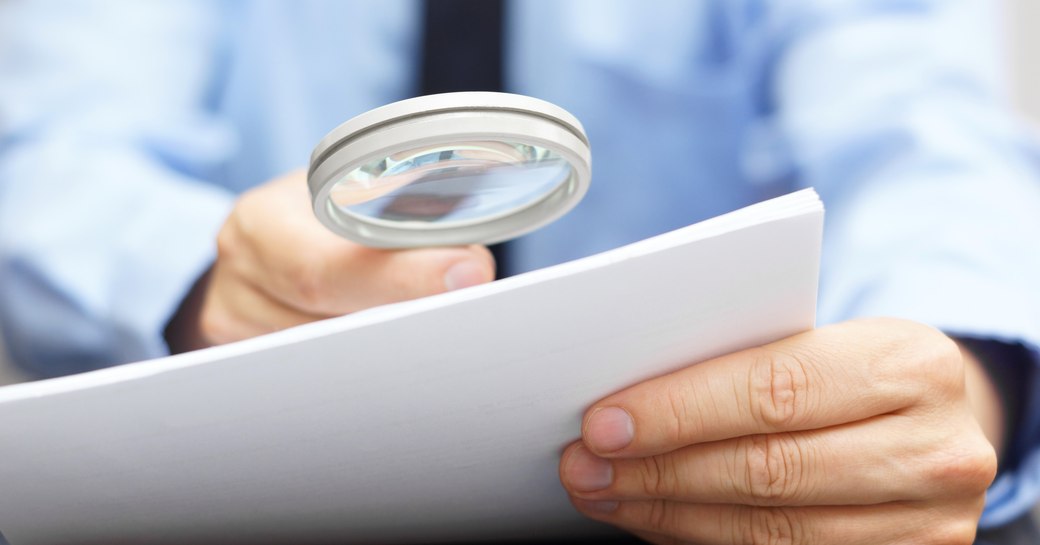 A man reviews a document with a magnifying glass