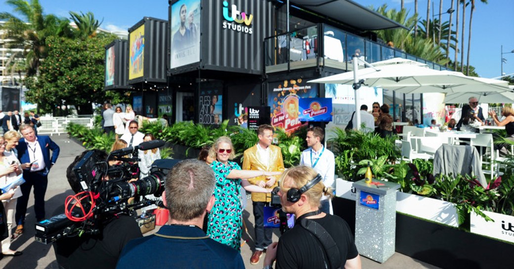 Exterior view of ITV stand at MIPCOM, camera crew and presenters working outside.