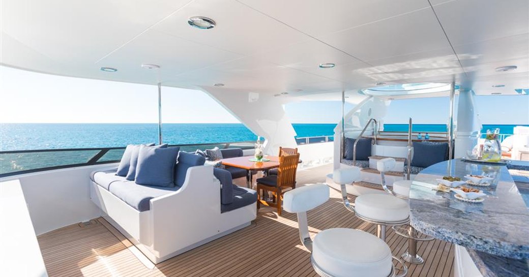 Overview of the aft deck onboard charter yacht MISS STEPHANIE, wt bar in foreground, with bench seating in the background.