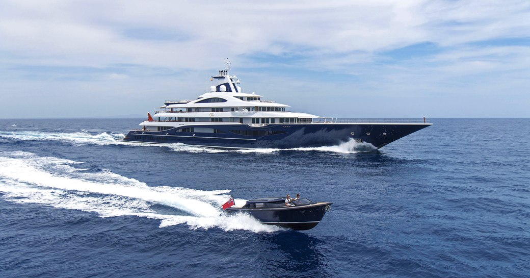 motor yacht Tis cruising the waters on her charter with her onboard tender cruising right beside her