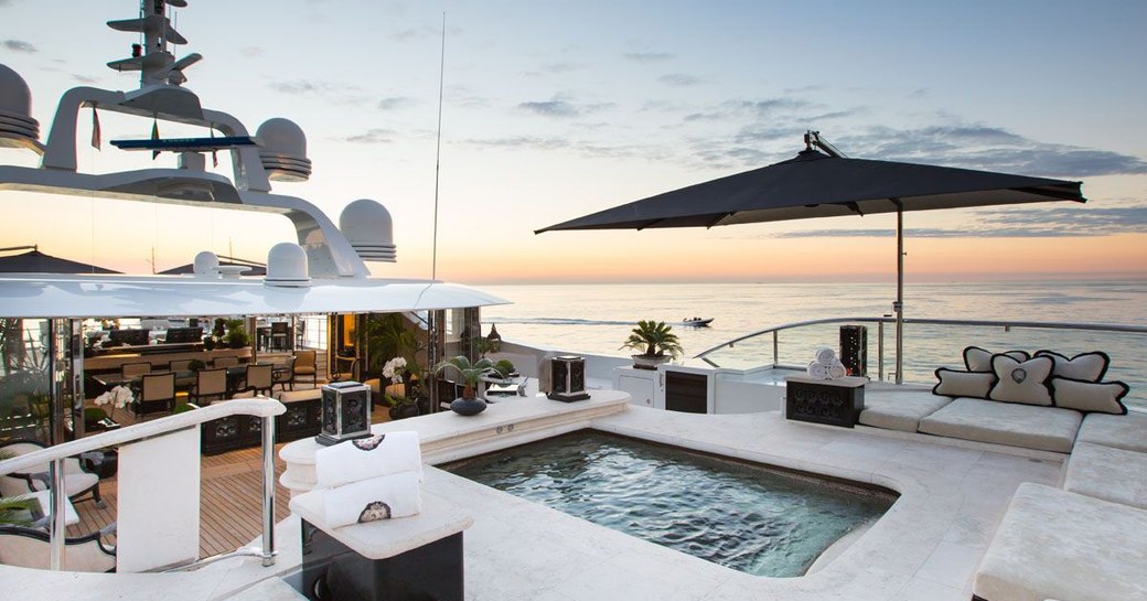 the sundeck of charter yacht lioness v featuring alfresco dining arangment and swimming pool surrounded by luxury cundaps