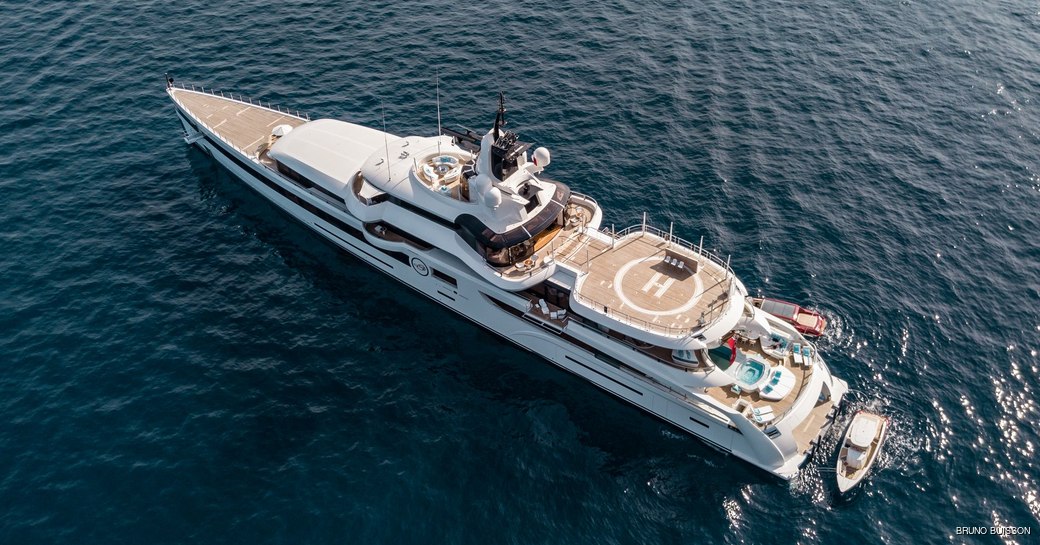 aerial shot os Feadship's Lady S as she elegantly cruises on her charter and also showing off her spacious sun deck, aft swimming pool, and hellipad