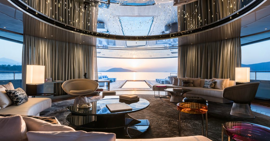 beautiful main salon looks out across the aft deck's swimming pool aboard charter yacht SAVANNAH 